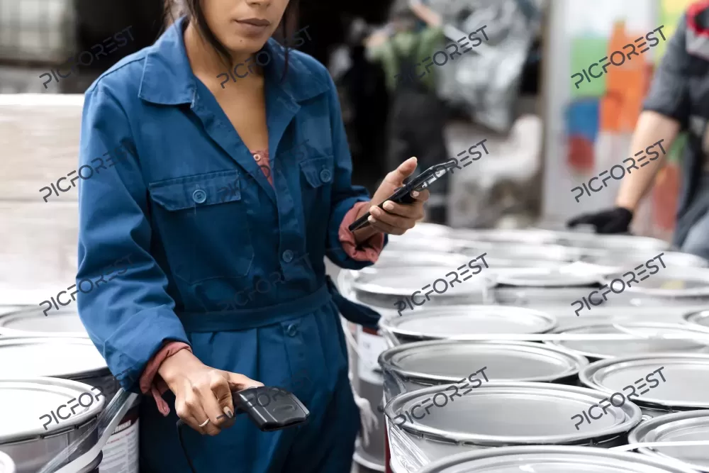 دانلود عکس زن جوان در حال کنترل محصولات در انبار